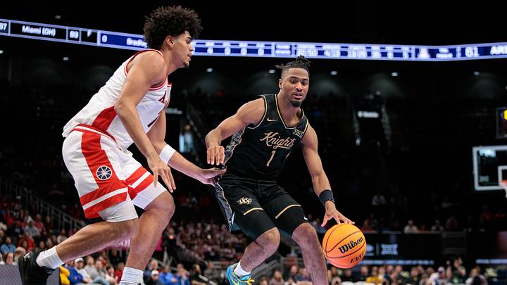 Mar 12, 2026; Kansas City, MO, USA; UCF Knights guard Themus Fulks (1) drives around Arizona Wildcats guard Jackson Francois (7) during the second half at T-Mobile Center. Mandatory Credit: William Purnell-Imagn Images