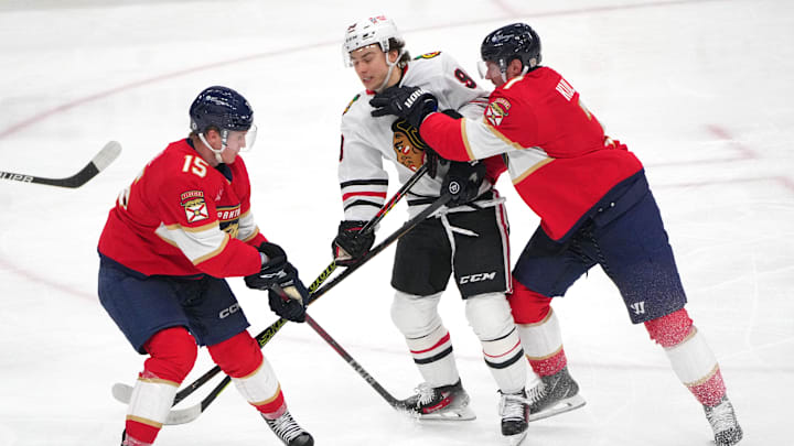 Feb 1, 2025; Sunrise, Florida, USA;  Florida Panthers defenseman Dmitry Kulikov (7) collides with Chicago Blackhawks center Connor Bedard (98) in the third period as center Anton Lundell (15) follows on the play at Amerant Bank Arena. Mandatory Credit: Jim Rassol-Imagn Images