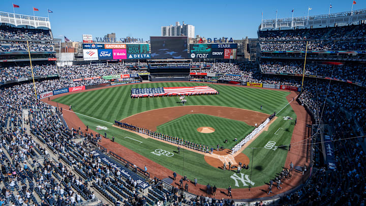 Both teams line the field during the singing of the national anthem prior to the start of the Opening Day game between the New York Yankees and Milwaukee Brewers at Yankee Stadium.