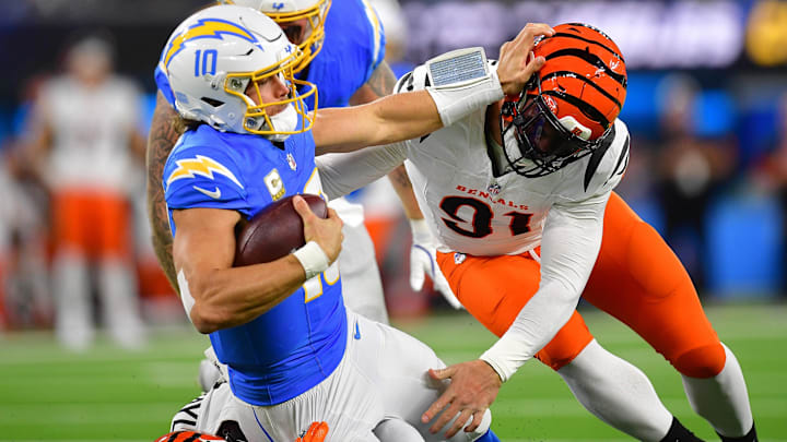 Nov 17, 2024; Inglewood, California, USA; Los Angeles Chargers quarterback Justin Herbert (10) is brought down by Cincinnati Bengals defensive end Trey Hendrickson (91) during the first half at SoFi Stadium. Mandatory Credit: Gary A. Vasquez-Imagn Images