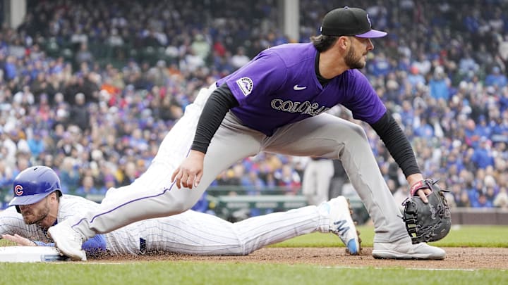 Apr 1, 2024; Chicago, Illinois, USA; Chicago Cubs left fielder Ian Happ (8) slides safely back into first base as Colorado Rockies first baseman Kris Bryant takes a late throw during the first inning at Wrigley Field.