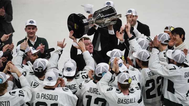 Michigan State hockey coach Adam Nightingale hoists the Big Ten tournament championship trophy after