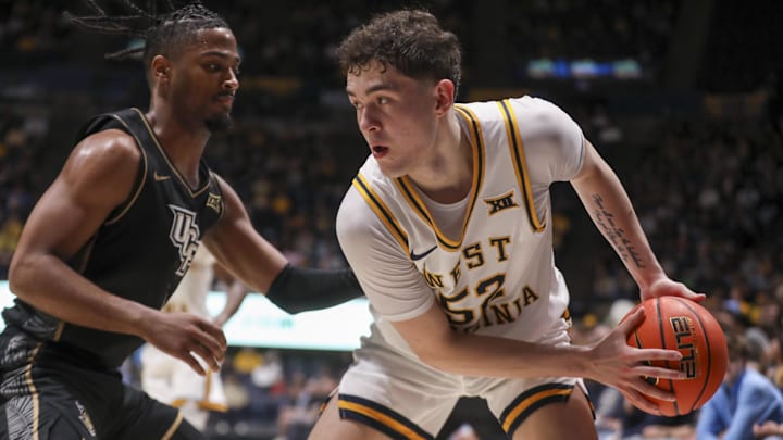 Mar 6, 2026; Morgantown, West Virginia, USA; West Virginia Mountaineers guard Treysen Eaglestaff (52) looks to make a move around UCF Knights guard Themus Fulks (1) during the second half at Hope Coliseum. Mandatory Credit: Ben Queen-Imagn Images