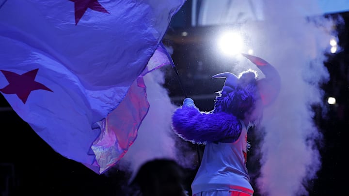 The Washington Wizards mascot waves a flag in a smokey arena. 