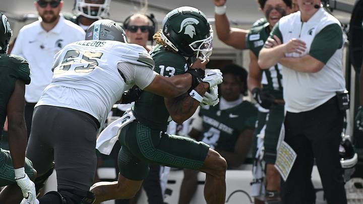 Sep 12, 2026; East Lansing, Michigan, USA;  Michigan State Spartans wide receiver Chrishon McCray (13) powers through a tackle on the sidelines in front of Michigan State Spartans head coach Pat Fitzgerald during the first quarter at Spartan Stadium.  Mandatory Credit: Dale Young-Imagn Images