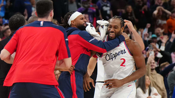 Mar 9, 2025; Inglewood, California, USA; LA Clippers forward Kawhi Leonard (2) celebrates with teammates after making the game-winning shot in overtime as Sacramento Kings coach Doug Christie watches at the Intuit Dome. Mandatory Credit: Kirby Lee-Imagn Images