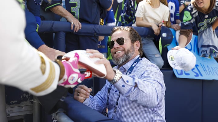 Oct 6, 2024; Seattle, Washington, USA; Seattle Seahawks general manager John Schneider signs autographs during pregame warmups against the New York Giants at Lumen Field.