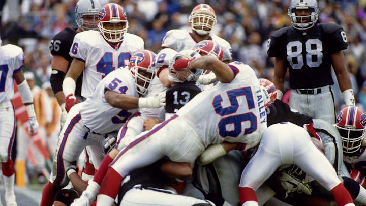Los Angeles Raiders quarterback Jay Schroeder (13) has his face mask pulled by Buffalo Bills linebacker Darryl Talley (56) and Carlton Bailey (54) at the Coliseum.