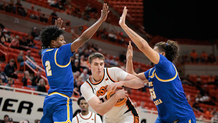 Feb 24, 2026; Stillwater, Oklahoma, USA; Oklahoma State Cowboys forward Andrija Vukovic (19) protects the ball between West Virginia Mountaineers guard Amir Jenkins (2) and West Virginia Mountaineers center Harlan Obioha (55) during the first half at Gallagher-Iba Arena. Mandatory Credit: William Purnell-Imagn Images
