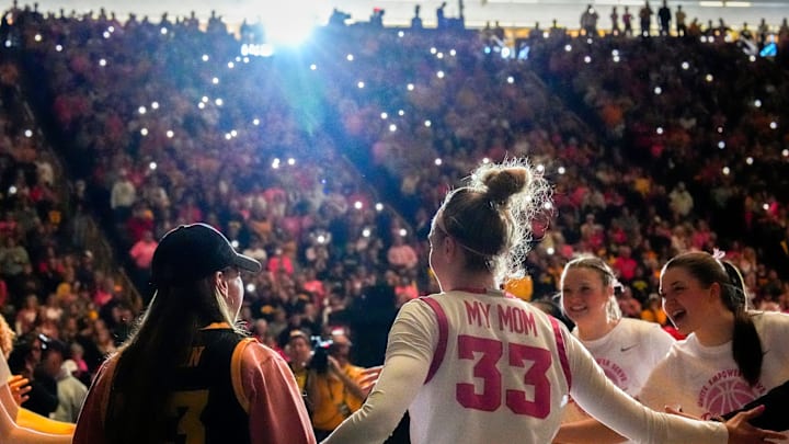 Iowa guard Lucy Olsen (33) walks onto the court during the starting lineup announcement with her mom, Kelley, during the “pink game” against the UCLA Bruins Sunday, Feb. 23, 2025 at Carver-Hawkeye Arena in Iowa City, Iowa.