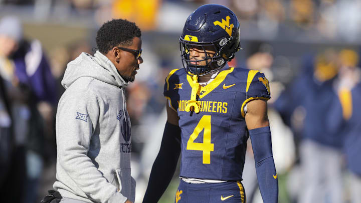 Nov 29, 2025; Morgantown, West Virginia, USA; West Virginia Mountaineers wide receiver Cam Vaughn (4) talks to West Virginia Mountaineers assistant coach Pat White during warmups prior to their game against the Texas Tech Red Raiders at Milan Puskar Stadium. Mandatory Credit: Ben Queen-Imagn Images