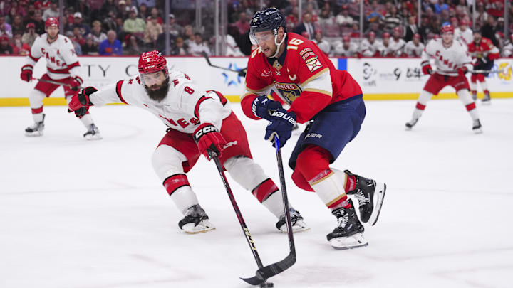 Jan 2, 2025; Sunrise, Florida, USA; Florida Panthers center Aleksander Barkov (16) skates the puck up the ice against Carolina Hurricanes defenseman Brent Burns (8) during the third period at Amerant Bank Arena. Mandatory Credit: Rich Storry-Imagn Images