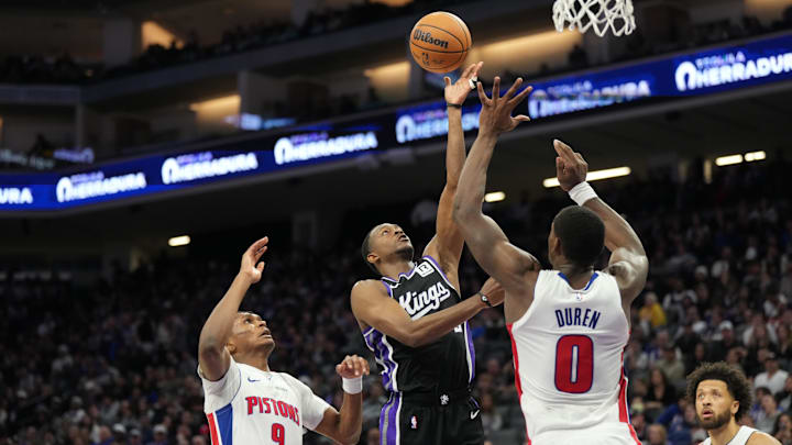 Dec 26, 2024; Sacramento, California, USA; Sacramento Kings guard De'Aaron Fox (5) shoots the ball between Detroit Pistons forward Ausar Thompson (9) and center Jalen Duren (0) during the fourth quarter at Golden 1 Center. Mandatory Credit: Kelley L Cox-Imagn Images