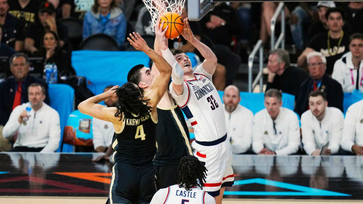 Connecticut Huskies center Donovan Clingan (32) shoots against Purdue Boilermakers center Zach Edey (15) and forward Trey Kaufman-Renn (4) in the first half in the national championship game of the 2024 NCAA Tournament at State Farm Stadium in Glendale on April 8, 2024.
