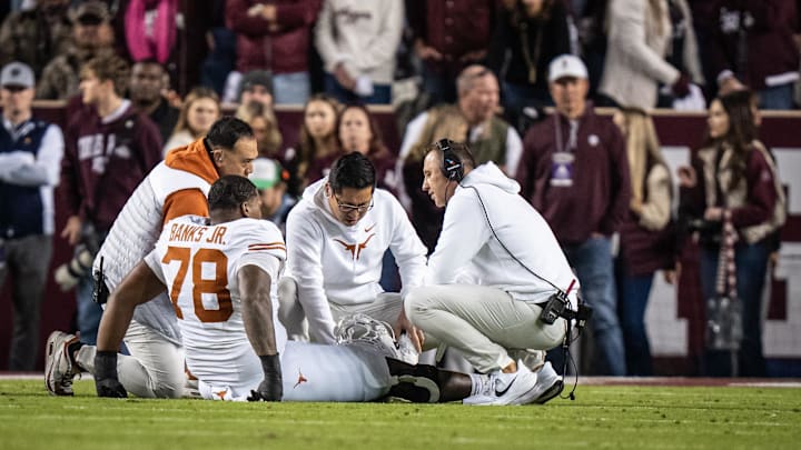 Nov 30, 2024; College Station, Texas, USA; Texas staff and Head Coach Steve Sarkisian attend to Texas Longhorns offensive lineman Kelvin Banks Jr. (78) after an injury in the first quarter of the Lone Star Showdown game against the Texas A&M Aggies at Kyle Field. Mandatory Credit: Sara Diggins/USA TODAY Network via Imagn Images