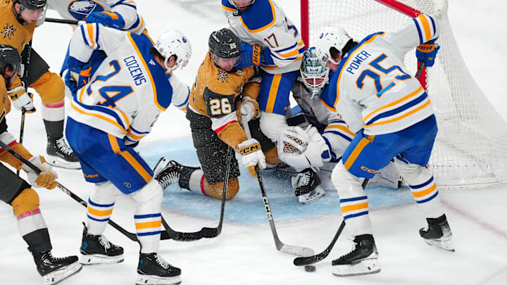 Jan 4, 2025; Las Vegas, Nevada, USA; Vegas Golden Knights right wing Alexander Holtz (26) is checked by Buffalo Sabres left wing Jason Zucker (17) in front of goaltender James Reimer (47) as defenseman Owen Power (25) collects a rebound during the third period at T-Mobile Arena. Mandatory Credit: Stephen R. Sylvanie-Imagn Images