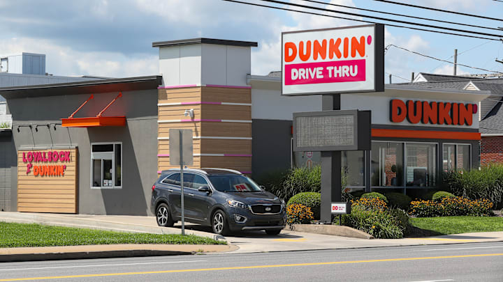 A car exits a Dunkin' drive thru. Dunkin' is the largest...