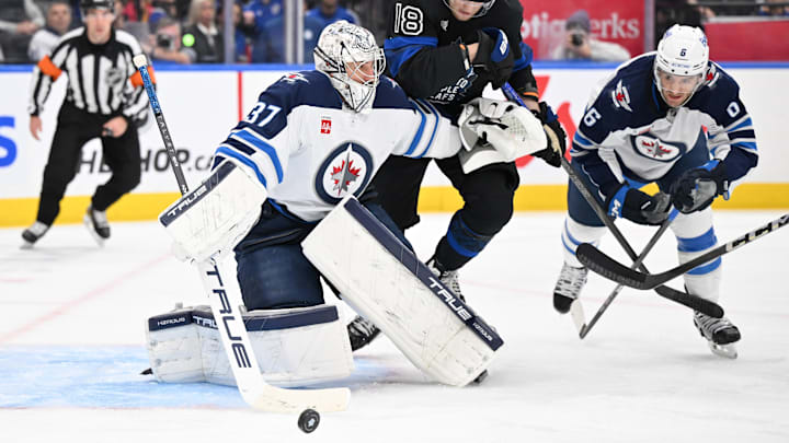 Dec 23, 2024; Toronto, Ontario, CAN;  Winnipg Jets goalie Connor Hellebuyck (37) makes a save as defenseman Colin Miller (6) and Toronto Maple Leafs forward Steven Lorentz (18) pursue the rebound in the third period at Scotiabank Arena. Mandatory Credit: Dan Hamilton-Imagn Images