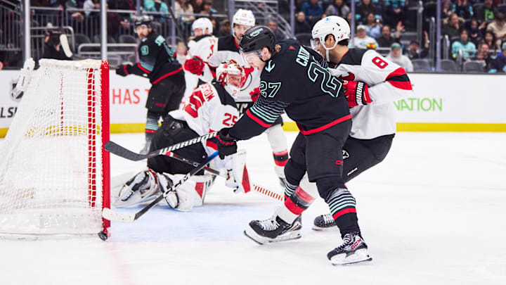 Jan 25, 2026; Seattle, Washington, USA; Seattle Kraken center Berkly Catton (27) takes a shot on goal as New Jersey Devils defenseman Johnathan Kovacevic (8) defends during the third period at Climate Pledge Arena. Mandatory Credit: Blake Dahlin-Imagn Images