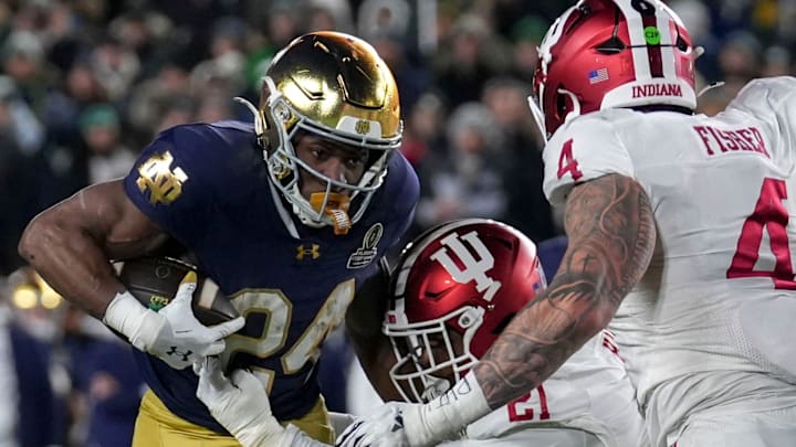 Indiana Hoosiers linebacker Rolijah Hardy (21) and linebacker Aiden Fisher (4) tackle Notre Dame Fighting Irish running back Jadarian Price (24) during the second half of a game between the Indiana Hoosiers and the Notre Dame Fighting Irish in first round of the College Football Playoff on Friday, Dec. 20, 2024, in South Bend. Notre Dame defeated Indiana 27-17. Indiana Hoosiers linebacker Rolijah Hardy (21) and linebacker Aiden Fisher (4) tackle Notre Dame Fighting Irish running back Jadarian Price (24) during the second half of a game between the Indiana Hoosiers and the Notre Dame Fighting Irish in first round of the College Football Playoff on Friday, Dec. 20, 2024, in South Bend. Notre Dame defeated Indiana 27-17.