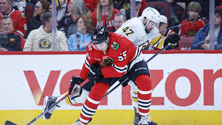 Jan 17, 2026; Chicago, Illinois, USA; Chicago Blackhawks defenseman Artyom Levshunov (55) battles for the puck with Boston Bruins center Mark Kastelic (47) during the first period at United Center. Mandatory Credit: Kamil Krzaczynski-Imagn Images