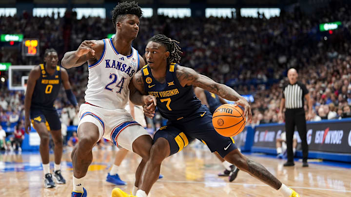 Dec 31, 2024; Lawrence, Kansas, USA; West Virginia Mountaineers guard Javon Small (7) drives against Kansas Jayhawks forward KJ Adams Jr. (24) during the first half at Allen Fieldhouse. Mandatory Credit: Jay Biggerstaff-Imagn Images