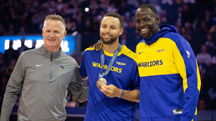Oct 11, 2024; San Francisco, California, USA; Golden State Warriors guard Stephen Curry (center) is flanked by head coach Steve Kerr and forward Draymond Green as he is presented his gold medal for his performance for Team USA at the 2024 Summer Olympics in Paris before taking on the Sacramento Kings at Chase Center. Mandatory Credit: D. Ross Cameron-Imagn Images Oct 11, 2024; San Francisco, California, USA; Golden State Warriors guard Stephen Curry (center) is flanked by head coach Steve Kerr and forward Draymond Green as he is presented his gold medal for his performance for Team USA at the 2024 Summer Olympics in Paris before taking on the Sacramento Kings at Chase Center. Mandatory Credit: D. Ross Cameron-Imagn Images