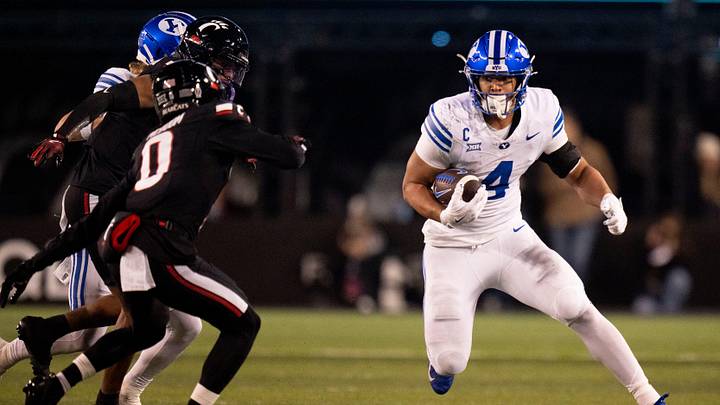BYU Cougars running back LJ Martin (4) runs the ball as Cincinnati Bearcats cornerback Matthew McDoom (0) defends in the third quarter of the NCAA football game at Nippert Stadium in Cincinnati on Nov. 22, 2025.