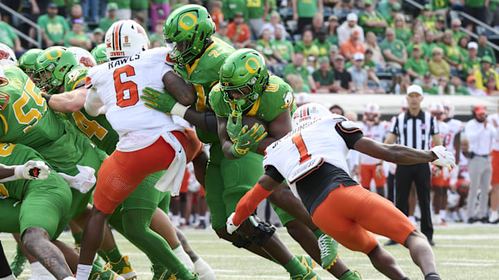 Sep 6, 2025; Eugene, Oregon, USA; Oregon Ducks running back Jordon Davison (0) scores a touchdown during the second half against Oklahoma State Cowboys cornerback JK Johnson (1) at Autzen Stadium. Mandatory Credit: Troy Wayrynen-Imagn Images