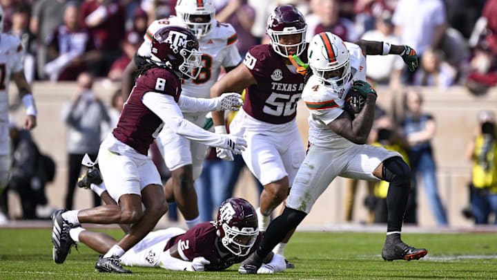 Dec 20, 2025; College Station, TX, USA; Miami Hurricanes running back Mark Fletcher Jr. (4) eludes the tackle of Texas A&M Aggies cornerback Dezz Ricks (2) and cornerback Jordan Shaw (8) during the game between the Aggies and the Hurricanes at Kyle Field. Mandatory Credit: Jerome Miron-Imagn Images