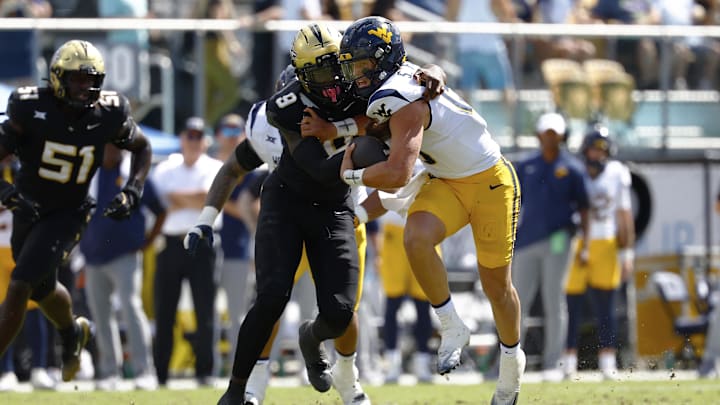 Oct 18, 2025; Orlando, Florida, USA;  West Virginia Mountaineers quarterback Scotty Fox Jr. (15) is tackled by Central Florida Knights linebacker Nyjalik Kelly (9) in the first half for a fourth down stop at Acrisure Bounce House. Mandatory Credit: Russell Lansford-Imagn Images