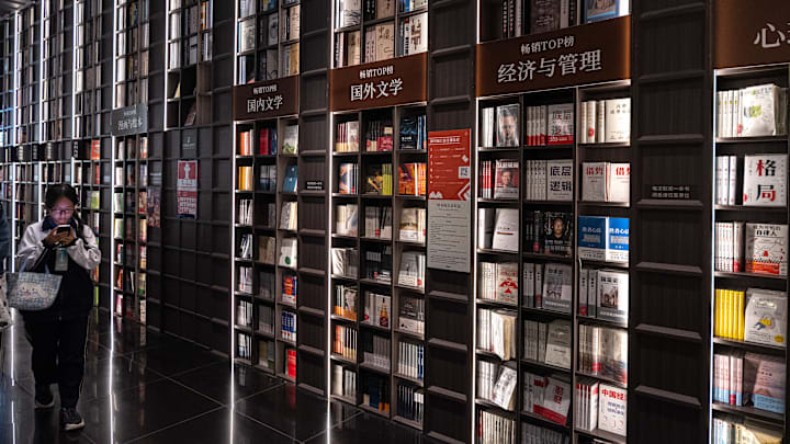 A woman seen walking past a bookshelf at the Zhongshuge...