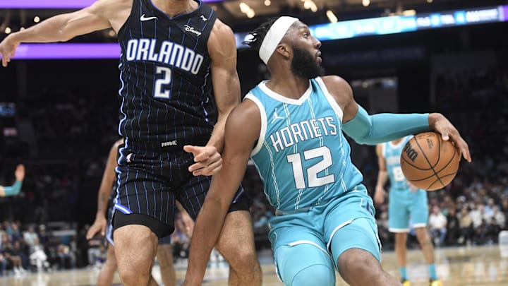 Mar 25, 2025; Charlotte, North Carolina, USA;  Charlotte Hornets guard Josh Okogie (12) puts a spin move on Orlando Magic forward Caleb Houstan (2) during the second half at the Spectrum Center. Mandatory Credit: Sam Sharpe-Imagn Images