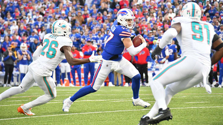 Buffalo Bills quarterback Josh Allen (17) runs between Miami Dolphins safety Marcus Maye (26) and linebacker Emmanuel Ogbah (91).