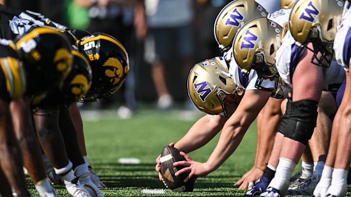 The Husky and Iowa lines prepare for the snap of the ball. 
