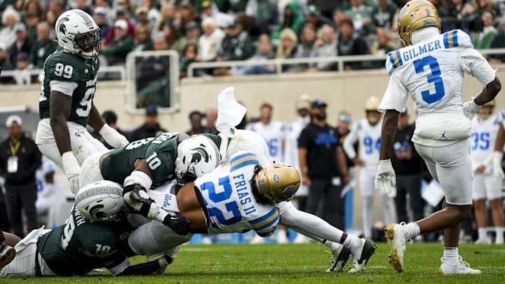 Oct 11, 2025; East Lansing, Michigan, USA; UCLA Bruins running back Anthony Frias II (22) rushes the ball against  Michigan State linebacker Wayne Matthews (10) and defensive back Armorion Smith (19) in the third quarter at Spartan Stadium. Mandatory Credit: Brendan Mullin-Imagn Images