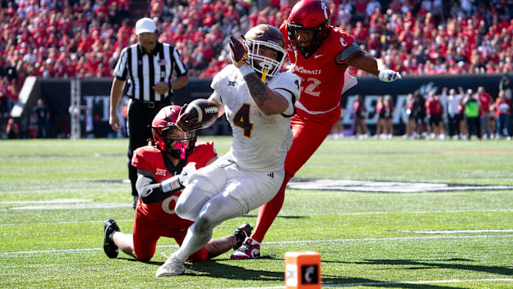 Arizona State Sun Devils running back Cam Skattebo (4) scores a touchdown as Cincinnati Bearcats defensive back Josh Minkins (0) and linebacker Jonathan Thompson (22) attempt to stop him in the third quarter.