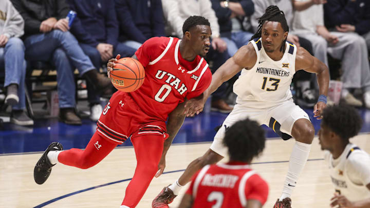 Feb 18, 2026; Morgantown, West Virginia, USA; Utah Utes forward Seydou Traore (0) dribbles against West Virginia Mountaineers guard Chance Moore (13) during the first half at Hope Coliseum. Mandatory Credit: Ben Queen-Imagn Images