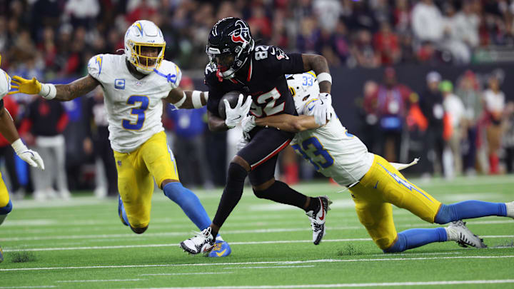 Jan 11, 2025; Houston, Texas, USA; Houston Texans wide receiver Diontae Johnson (82) runs the ball after a reception against Los Angeles Chargers defensive back Deane Leonard (33) and safety Derwin Jarnes Jr. (3) during the third quarter in an AFC wild card game at NRG Stadium.