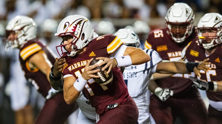 ULM Warhawks' quarterback General Booty (14) avoids Jackson State Tigers' players during the game in Monroe, La., on Thursday, Aug. 29, 2024.