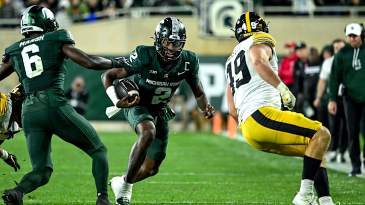 Michigan State's Aidan Chiles, center, runs for a big gain as Iowa's Ethan Hurkett closes in during the third quarter on Saturday, Oct. 19, 2024, at Spartan Stadium in East Lansing.