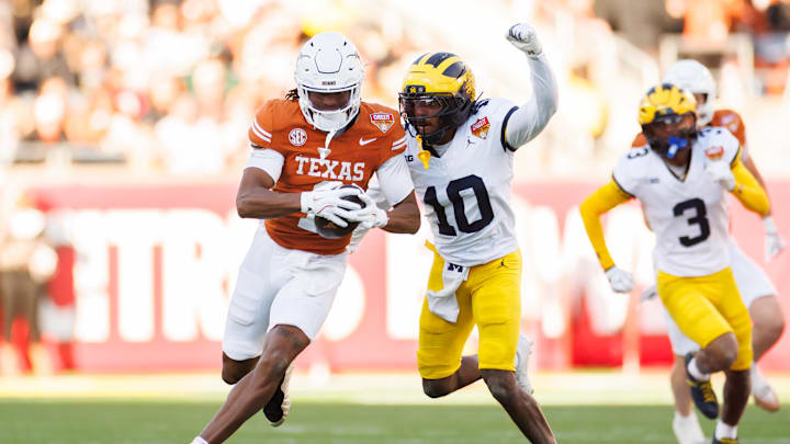 Dec 31, 2025; Orlando, FL, USA; Texas Longhorns wide receiver Ryan Wingo (1) runs with the ball while Michigan Wolverines defensive back Zeke Berry (10) attempts to tackle during the first half at Camping World Stadium. Mandatory Credit: Matt Pendleton-Imagn Images
