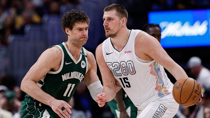Mar 26, 2025; Denver, Colorado, USA; Denver Nuggets center Nikola Jokic (15) controls the ball as Milwaukee Bucks center Brook Lopez (11) guards in the fourth quarter at Ball Arena. Mandatory Credit: Isaiah J. Downing-Imagn Images