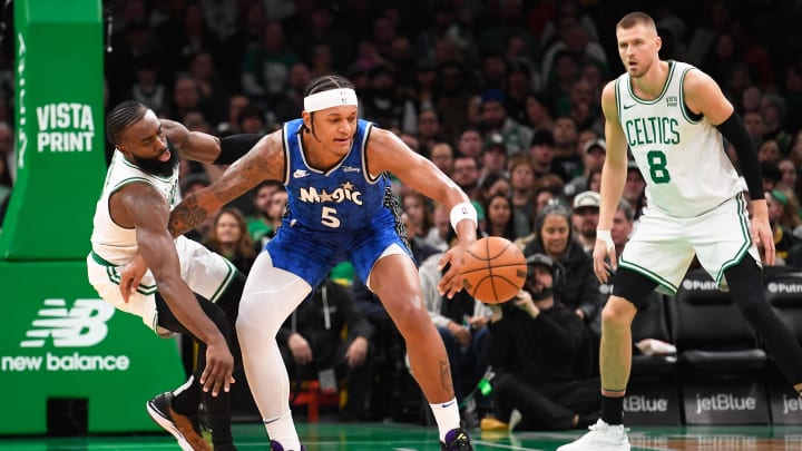 Dec 17, 2023; Boston, Massachusetts, USA;  Orlando Magic forward Paolo Banchero (5) dribbles away from Boston Celtics guard Jaylen Brown (7) during the second half at TD Garden.