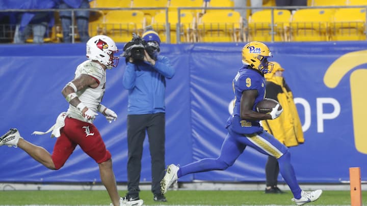 Oct 14, 2023; Pittsburgh, Pennsylvania, USA; Pittsburgh Panthers wide receiver Konata Mumpfield (9) crosses the goal line for a touchdown as Louisville Cardinals defensive back Cam'Ron Kelly (11) chases during the fourth quarter at Acrisure Stadium. Pittsburgh won 38-21. Mandatory Credit: Charles LeClaire-Imagn Images Oct 14, 2023; Pittsburgh, Pennsylvania, USA; Pittsburgh Panthers wide receiver Konata Mumpfield (9) crosses the goal line for a touchdown as Louisville Cardinals defensive back Cam'Ron Kelly (11) chases during the fourth quarter at Acrisure Stadium. Pittsburgh won 38-21. Mandatory Credit: Charles LeClaire-Imagn Images