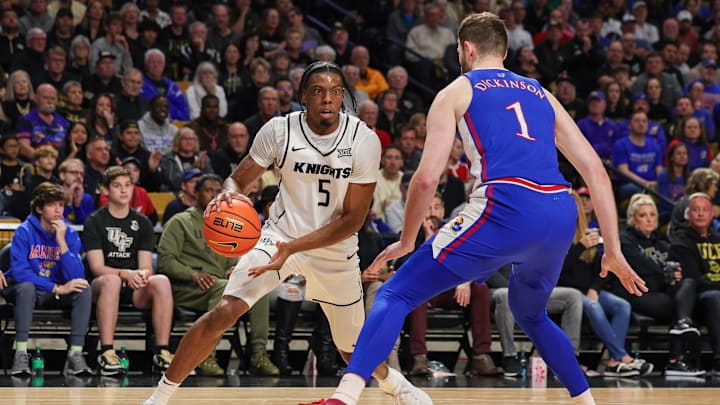 Jan 10, 2024; Orlando, Florida, USA; UCF Knights forward Omar Payne (5) handles the ball in front of Kansas Jayhawks center Hunter Dickinson (1) during the second half at Addition Financial Arena. Mandatory Credit: Mike Watters-Imagn Images