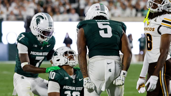 Michigan State's Jordan Hall and Joshua Eaton celebrate with Wayne Matthew III after he makes an interception.