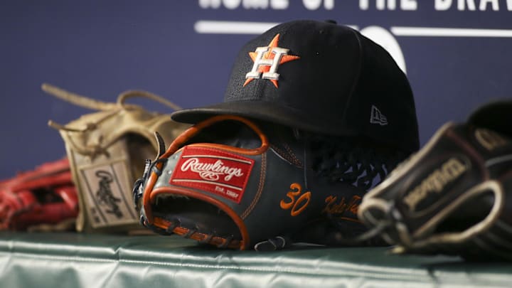 A Houston Astros hat sits on a glove in the dugout