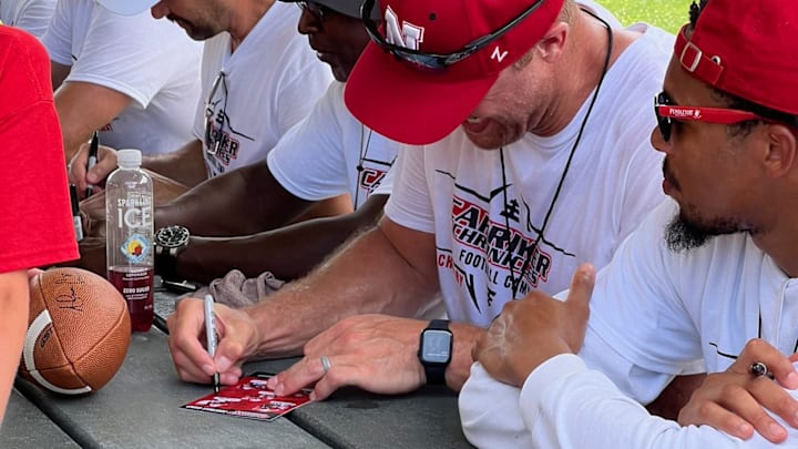 Adam Carriker signs autographs at his youth football camp alongside other Husker legends.