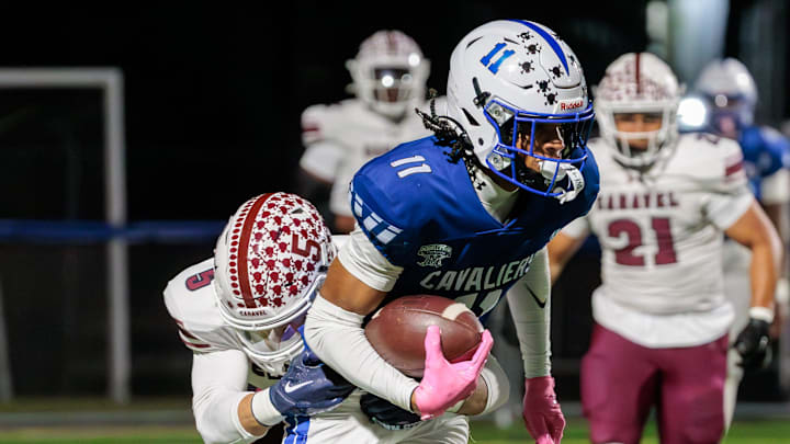 Caravel defensive back Richie Massey (left) dives to bring down Middletown receiver DJ Davis after a catch and run in the first quarter of the Cavaliers’ 28-7 win over the Buccaneers at Cavalier Stadium on Oct. 17, 2025.